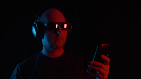 在黑暗中使用智能手机的耳机和太阳镜的人视频