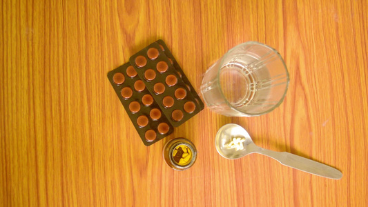 勺子瓶子和一杯水中的药丸或药片的顶部视图以及木桌背景视频