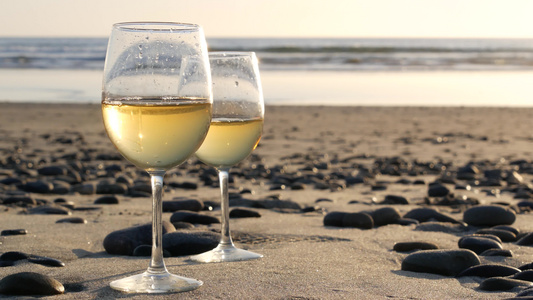 两杯红酒在海边一杯白葡萄酒用于浪漫约会海水日落波浪视频