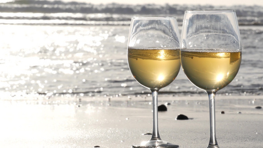 两杯红酒在海边一杯白葡萄酒用于浪漫约会海水日落波浪视频