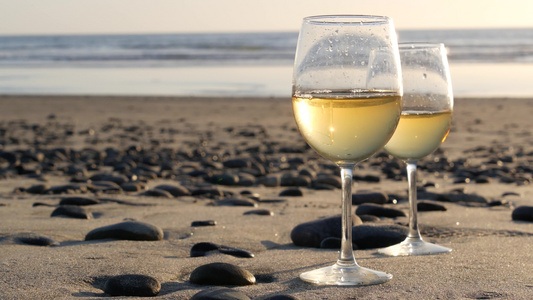 两杯红酒在海边一杯白葡萄酒用于浪漫约会海水日落波浪视频