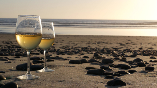 两杯红酒在海边一杯白葡萄酒用于浪漫约会海水日落波浪视频