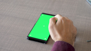 餐桌上的手触摸绿色屏幕的手机12秒视频