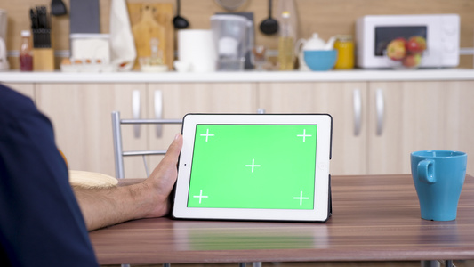 男人在厨房看数字平板电脑视频