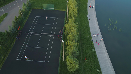 在绿色城市公园的一个球场上玩网球的球员飞回来空中最高视频