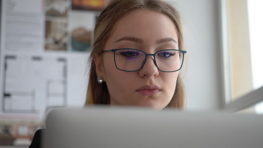 戴眼镜的美丽女女工程师在创意办公室用笔记本电脑工作视频