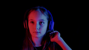美丽的少女在霓虹灯的黑暗房间里听音乐耳机放松的女孩13秒视频
