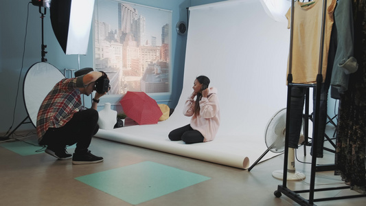 照片拍摄的后台黑色模特坐在地板上为摄影师摆姿势视频