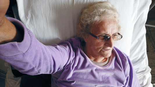 孤独的老年妇女在医院病房白床单上沉浸着深思视频