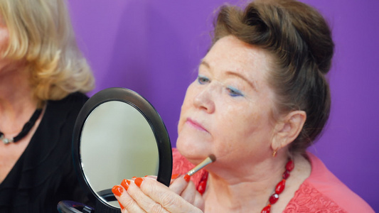 老妇人照镜子用化妆刷化妆视频