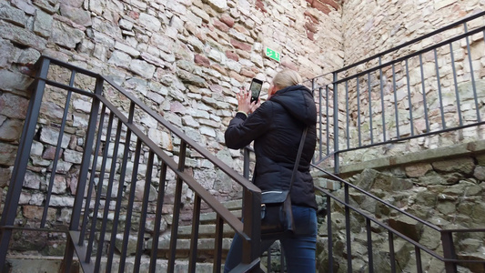 一个女孩走过古老的城堡拍着照片视频
