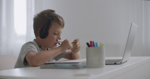 小男孩通过耳机用麦克风在网上聊天看笔记本电脑和绘画23秒视频
