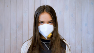 十几岁的女孩戴着医用防护面罩看着相机爆发浅灰色墙壁6秒视频