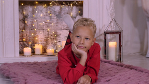 在圣诞节壁炉背景上躺在舒适地毯上的十几岁男孩的肖像11秒视频
