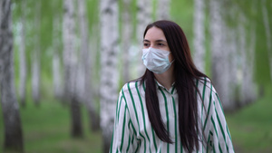 戴着口罩的年轻女孩在森林中行走17秒视频