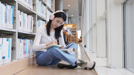 坐在图书馆角落听音乐看书写字的女大学生视频