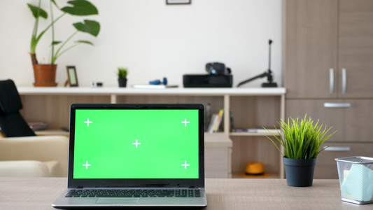 用绿色屏幕的笔记本电脑模拟在客厅中间的桌子上视频