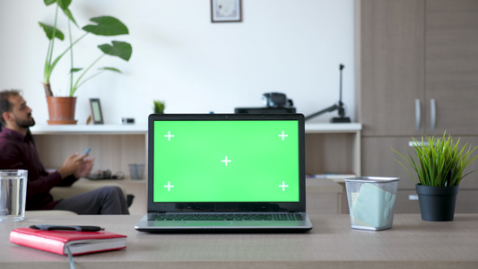 书桌上的笔记本电脑房子里有绿色屏幕视频