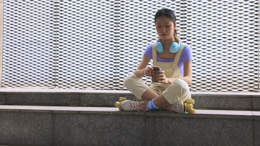 年轻女孩穿着轮滑鞋坐在台阶上喝咖啡休息视频