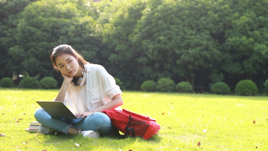 大学生在草地上用电脑学习视频