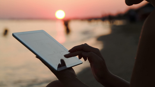 日落时在海滩与平板电脑合作的女孩视频