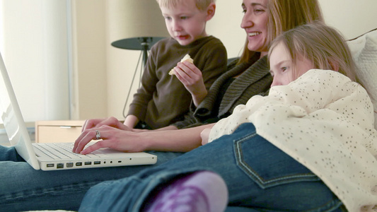 母亲带着两个孩子使用笔记本电脑视频