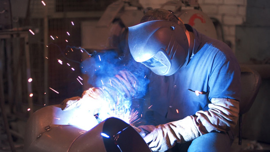工业人在金属加厂将钢焊接在保护面罩中视频
