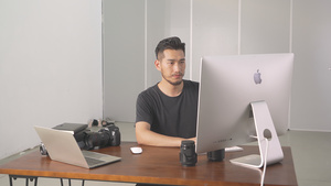 4K在电脑前认真工作的青年摄影师14秒视频