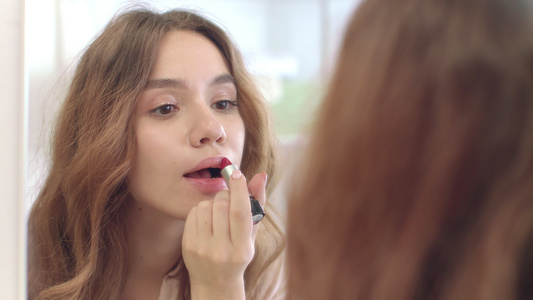 美丽的女人在家里用口红做唇膏化妆 前面的浴室镜子视频