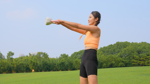 运动女性在草地上交叉训练平举壶铃45秒视频