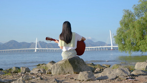 4k深圳湾海边弹吉他的少女背影16秒视频