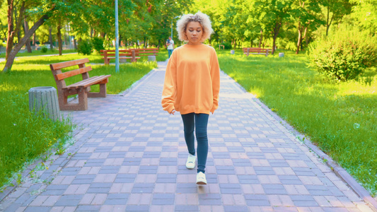 穿着黄色毛衣在公园散步的女孩视频