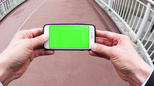 使用带绿色屏幕的智能手机的人的个人观点;在“绿屏”下视频