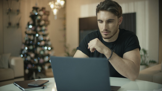 男子在圣诞节树上使用笔记本电脑视频