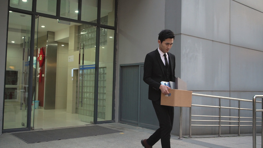 被辞退的白领拿着文件走出办公楼[踏进]视频