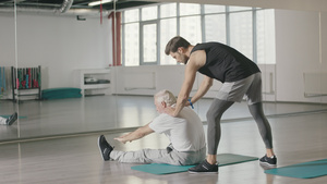 男子在健身房与教练一起做伸展运动13秒视频