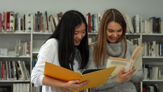 两名女学生在图书馆比较两本书中的信息视频