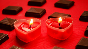 在红色背景下两个燃烧的爱心与巧克力块6秒视频