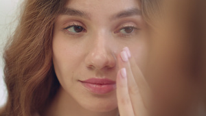 微笑的女人在脸部皮肤前卫生间镜子上涂润湿霜26秒视频