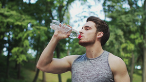 运动男子在夏季公园运动后从瓶中饮用水12秒视频
