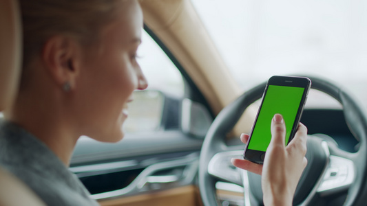 汽车驾驶座上女性愉快地使用手机打字有绿色屏幕视频