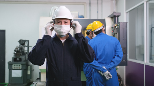 工厂工人戴面罩在后面与机器一起工作的团队视频