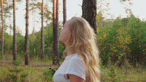 美丽的女孩在松林中行走的一面16秒视频