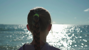 看日落和闪闪发光的海水的金发小女孩的特写10秒视频