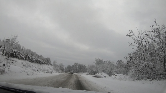 驾驶车在冬季积雪的雪地山路上行驶视频