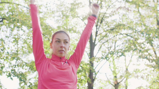 身体健康的女孩在公园里伸展她的手臂 在跑前先暖暖运动视频