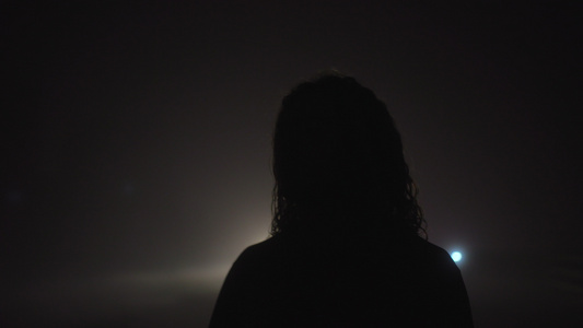 雾中夜间走在路边的年轻人剪影视频