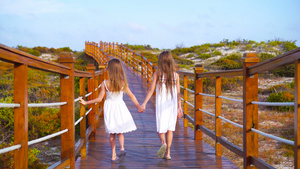 可爱的小姑娘们在去白色热带海滩的路上 在一座木桥上12秒视频