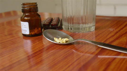 查看抗氧化剂维生素片、药丸水泡、一瓶药物、量匙中的胶囊，桌上放着一杯水。药房主题。侧视图，关闭与复制空间视频