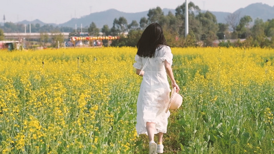 油菜花花海中奔跑的少女背影升格视频视频